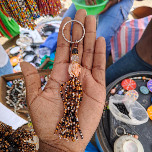 Handcrafted beaded tassel keychain with a marbled peach and white swirl amber focal bead made by Kibera artisans in Kenya.