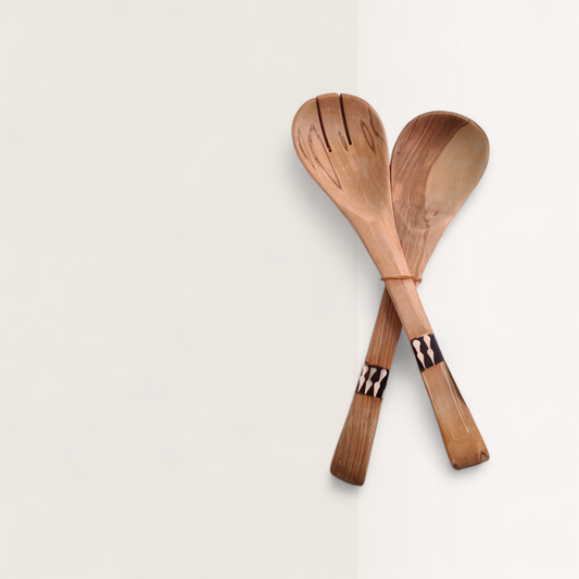 Two wooden spoons with decorative handles on a light beige background
