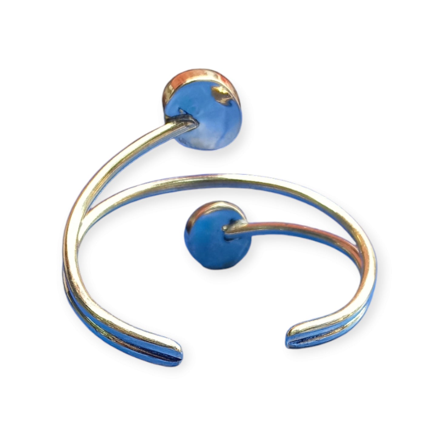 Brass cuff bracelet with two round glass ornaments, showing a swirling yellow and blue design, made in Kenya.