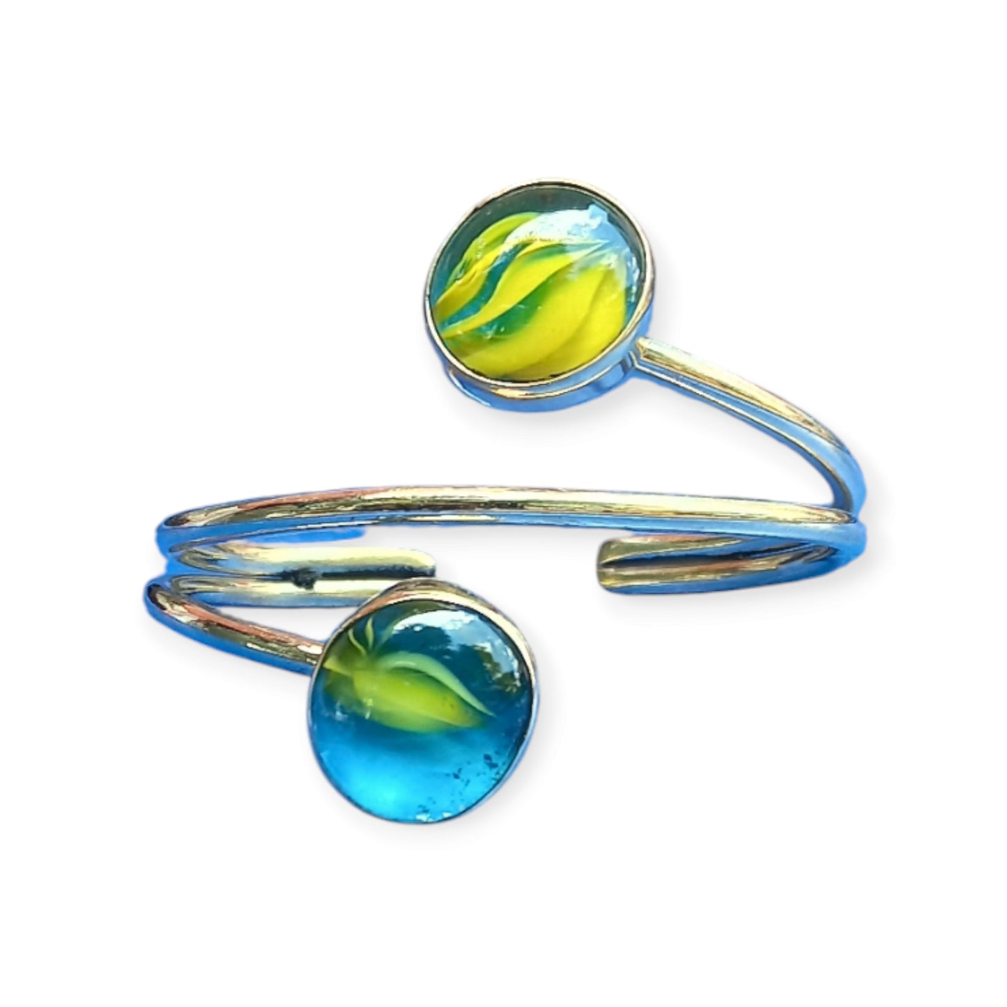 Brass cuff bracelet with two round glass ornaments, showing a swirling yellow and blue design, made in Kenya.