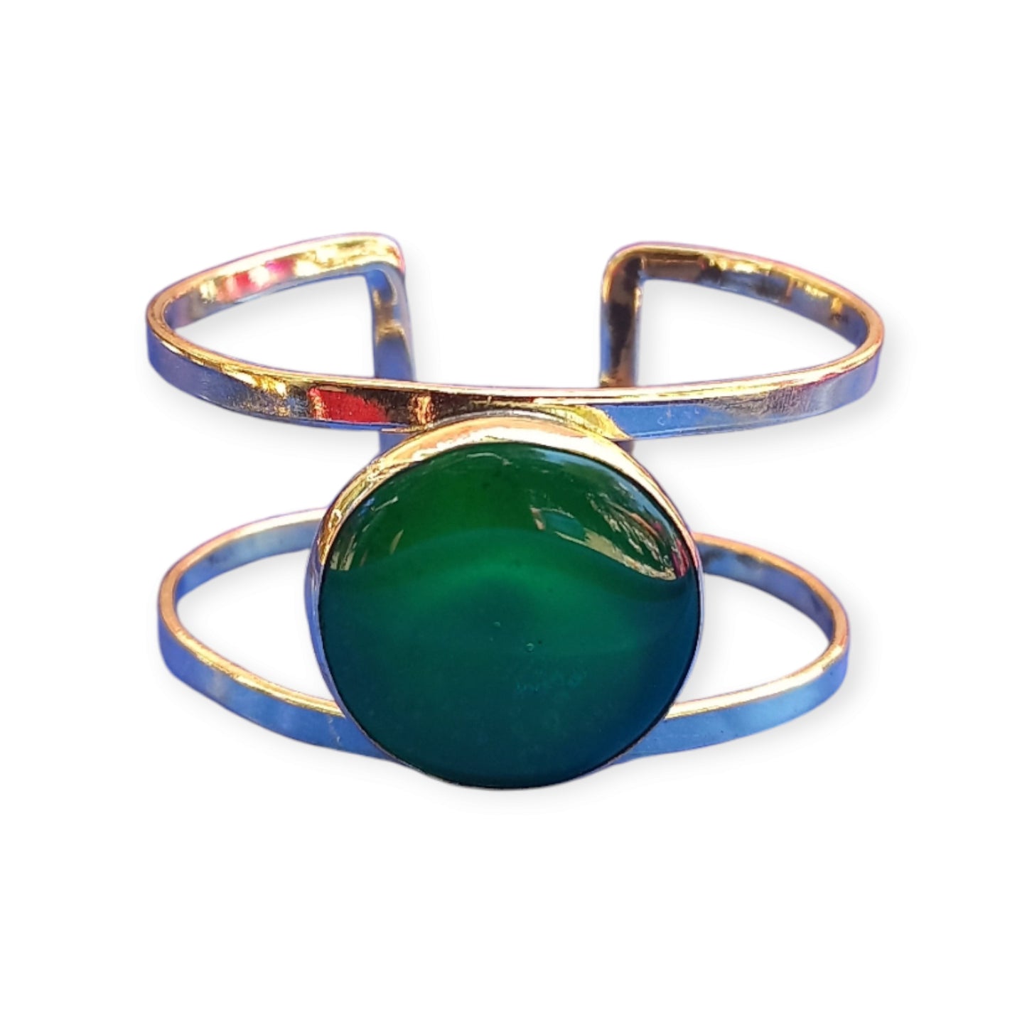 A handcrafted, adjustable brass bracelet from Kenya, designed as a double open cuff and featuring a striking, large emerald green amber ornament.