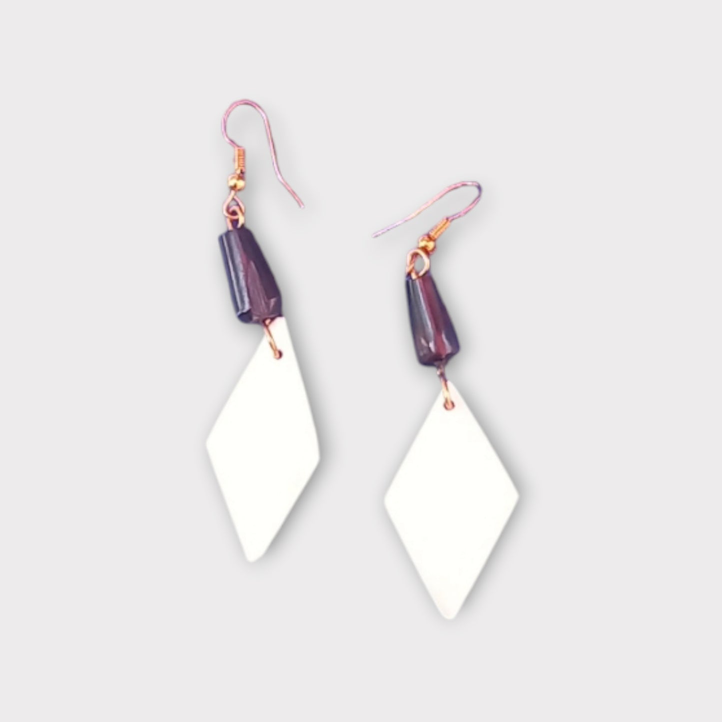 Handcrafted Kenyan earrings featuring a white diamond-shaped bone pendant and a dark accent bead.
