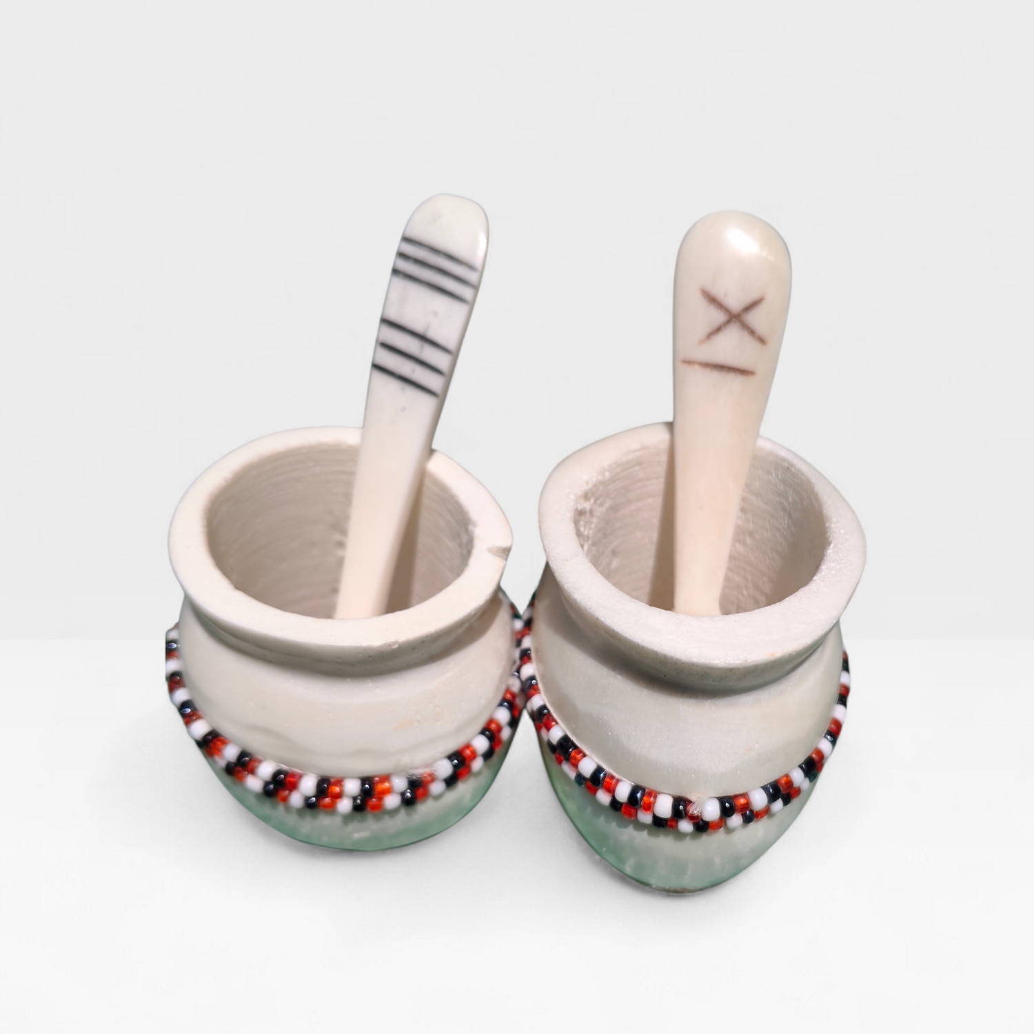 Handcrafted set of 2 cream bone spice pots with red black and white beads and etched bone spoons, made in Kibera Nairobi Kenya.