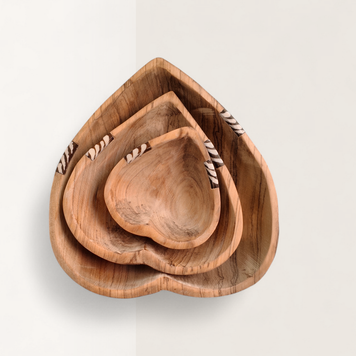 Handcrafted 3-piece nesting Kenyan olive wood heart bowls with zebra stripe batik bone inlay rim, made in Ukambani Kenya.