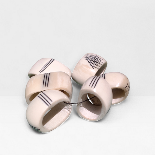 Set of 6 handcrafted Kenyan cow bone napkin rings with black etched line geometric patterns made in Kibera Kenya