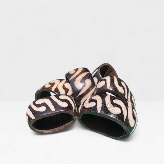 Set of 6 handcrafted Kenyan cow bone napkin rings with dark brown background and white batik swirl patterns made in Kibera Kenya