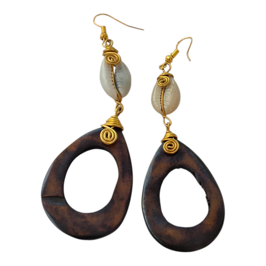 Hand-carved dark brown upcycled bone hollow teardrop statement earrings with wire-wrapped natural cowrie shells and brass coils, made in Kibera, Nairobi, Kenya.