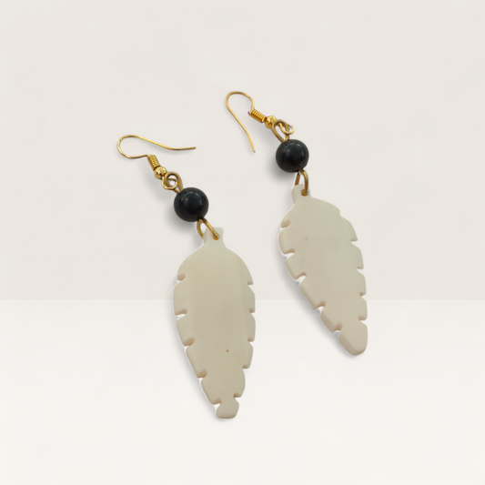 Handcrafted Kenyan earrings featuring white leaf-shaped bone carvings and black round beads on gold brass hooks