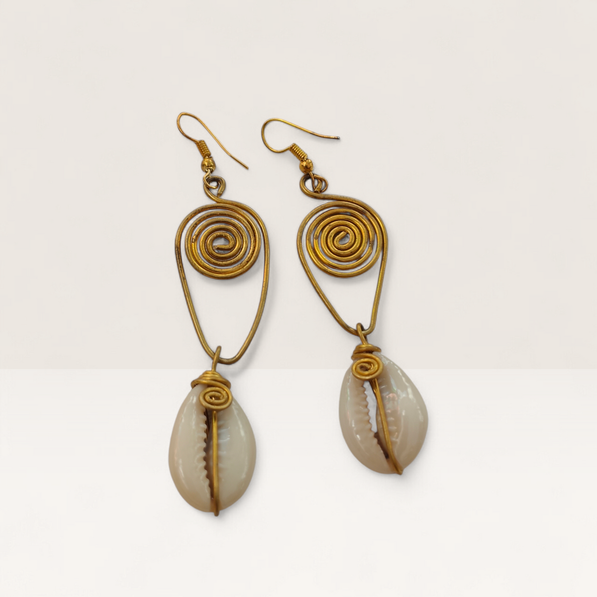 Handcrafted brass spiral dangle earrings with natural cowrie shell drop pendants, ethically made in Kibera, Nairobi, Kenya.
