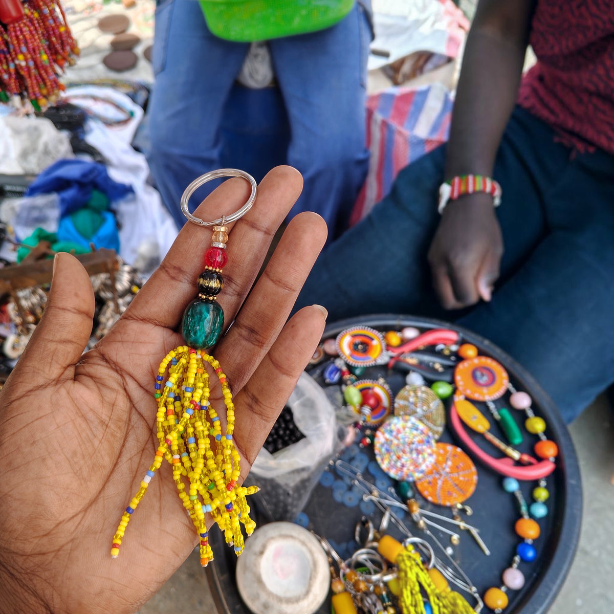 Handcrafted yellow beaded tassel keychain with a dark jade focal bead made in Kibera Kenya