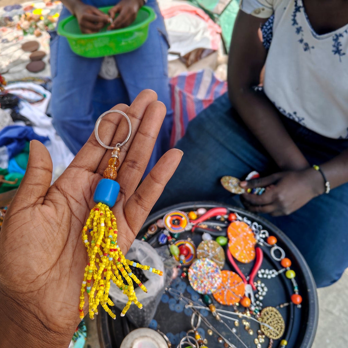 Handcrafted yellow beaded tassel keychain with a royal blue amber focal bead made by Kibera artisans in Kenya