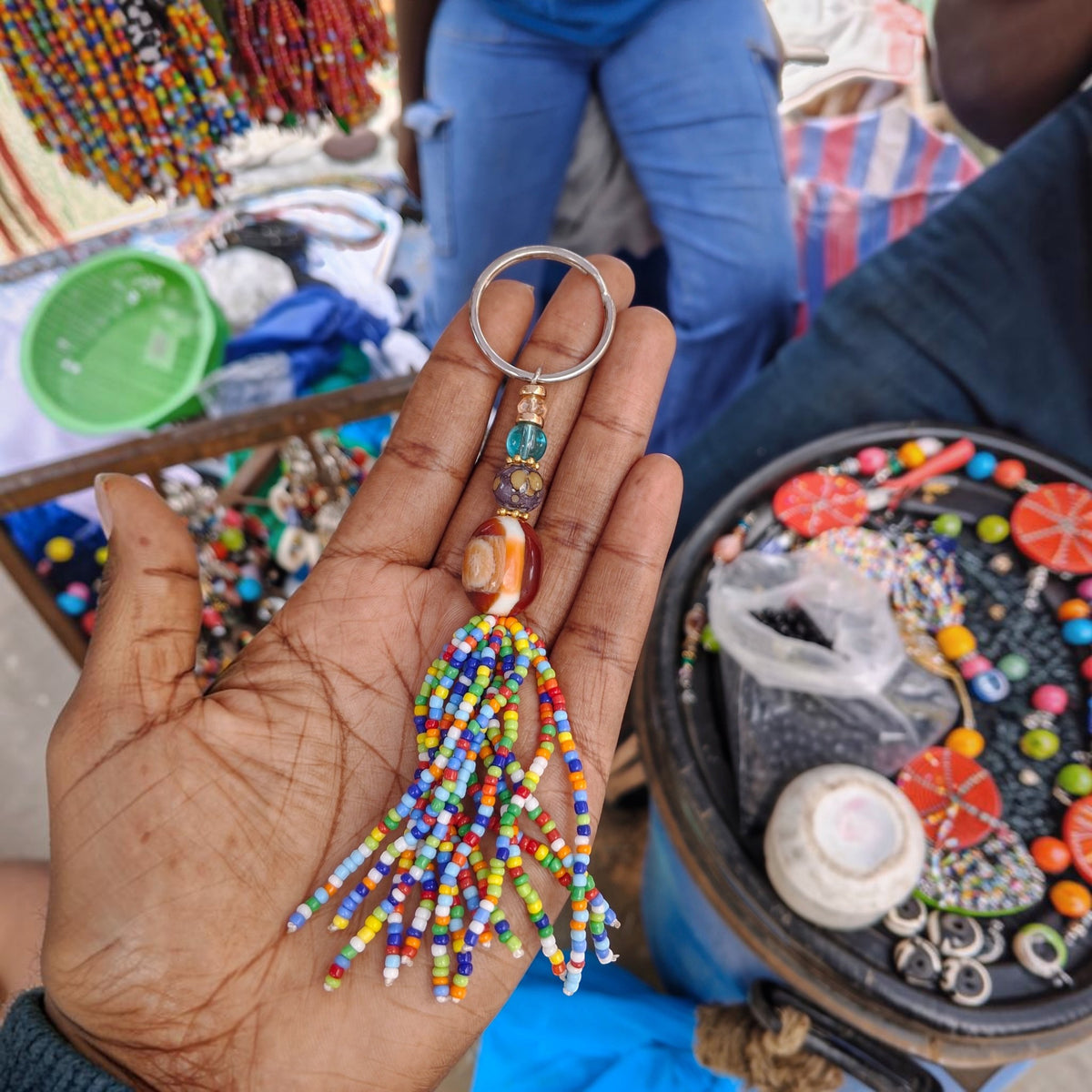 Handcrafted rainbow beaded tassel keychain with a carnelian amber focal bead made by Kibera artisans in Kenya.