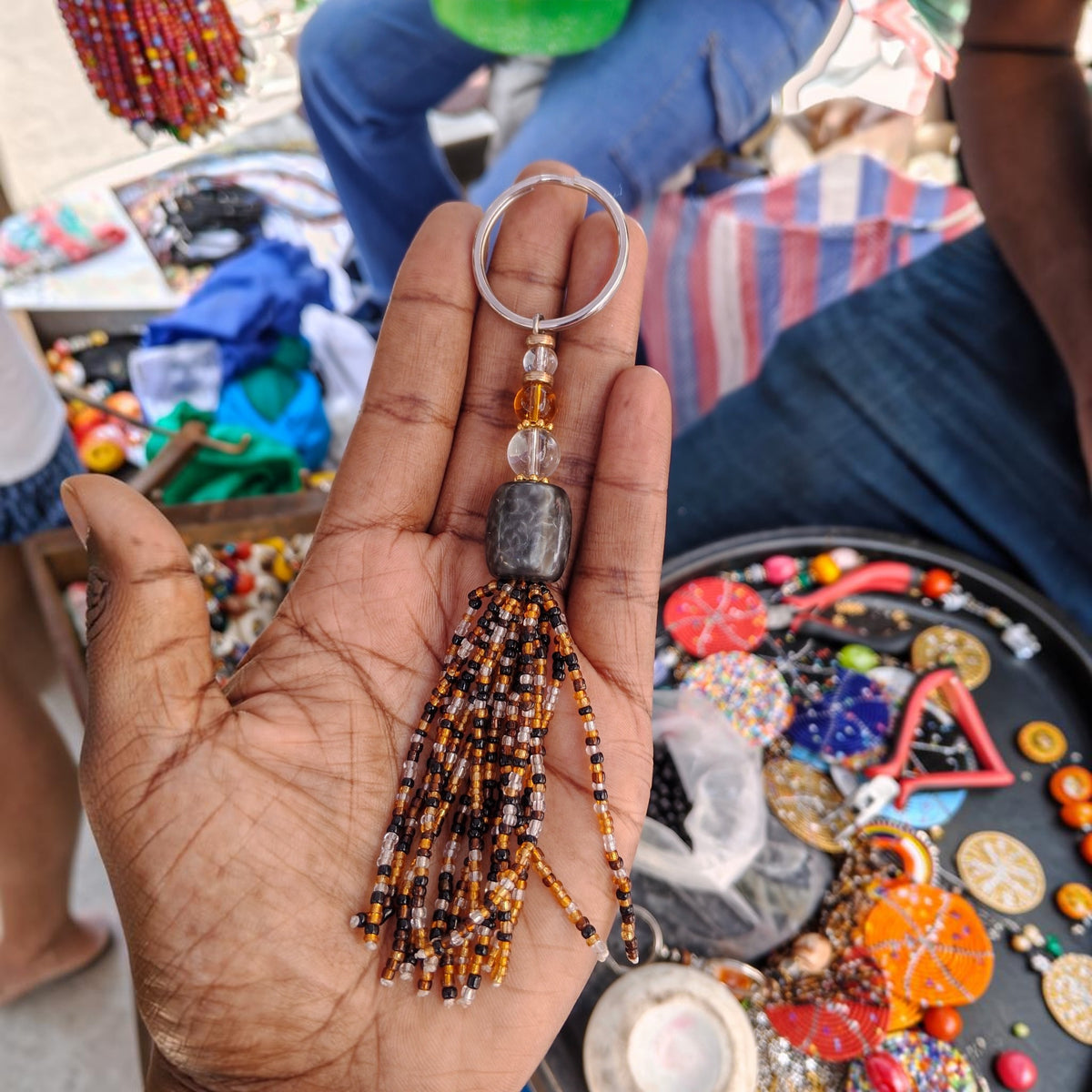 Handcrafted beaded tassel keychain with a charcoal black focal bead and stacked clear glass accents made in Kibera Kenya.