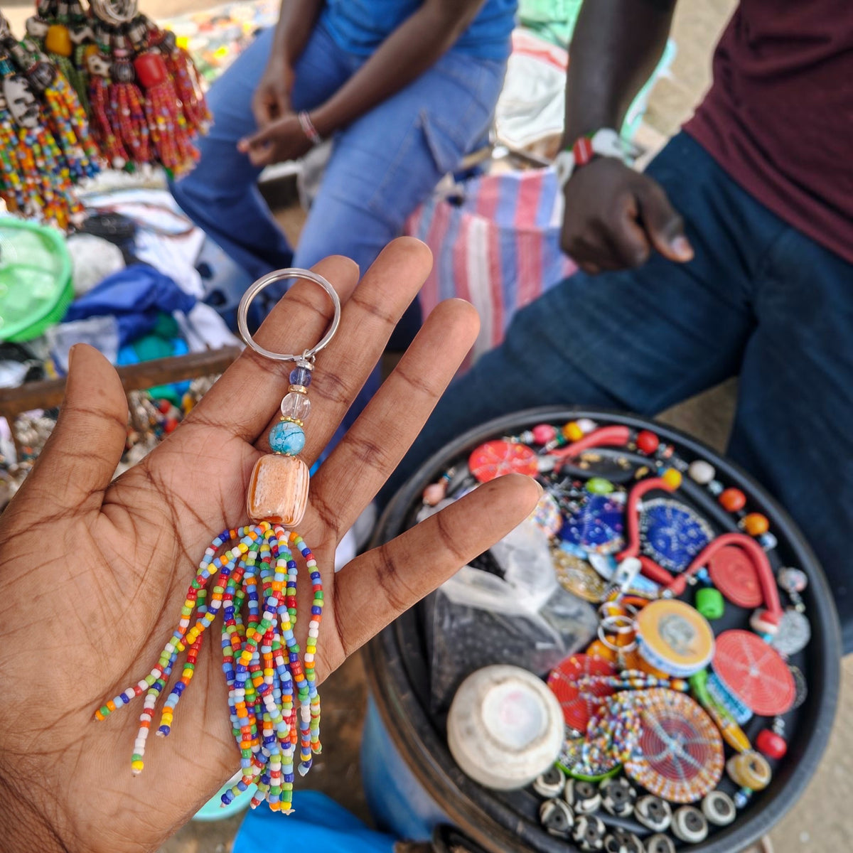 Handcrafted rainbow beaded tassel keychain featuring a swirled terracotta orange focal bead made in Kibera Kenya.