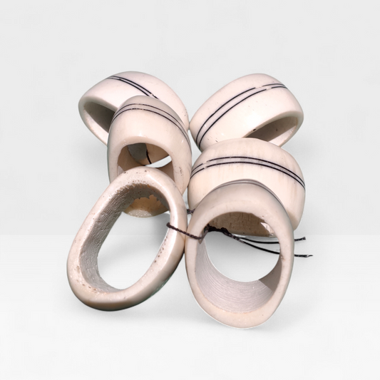 Set of six off-white upcycled cow bone napkin rings with minimalist double black line detail made in Kibera Kenya.