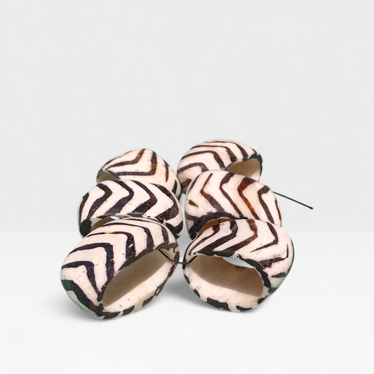 Set of six handcrafted upcycled cow bone napkin rings with black and white batik zebra chevron pattern made in Kibera Kenya.
