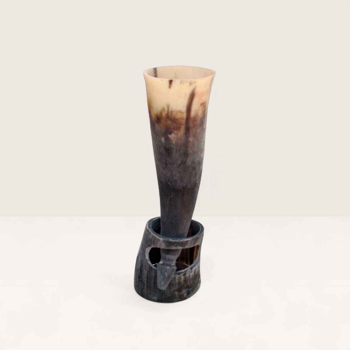 Handcrafted natural light cream and dark charcoal Kenyan cow horn Muratina drinking horn seated in its matching carved horn base, made in Kenya.