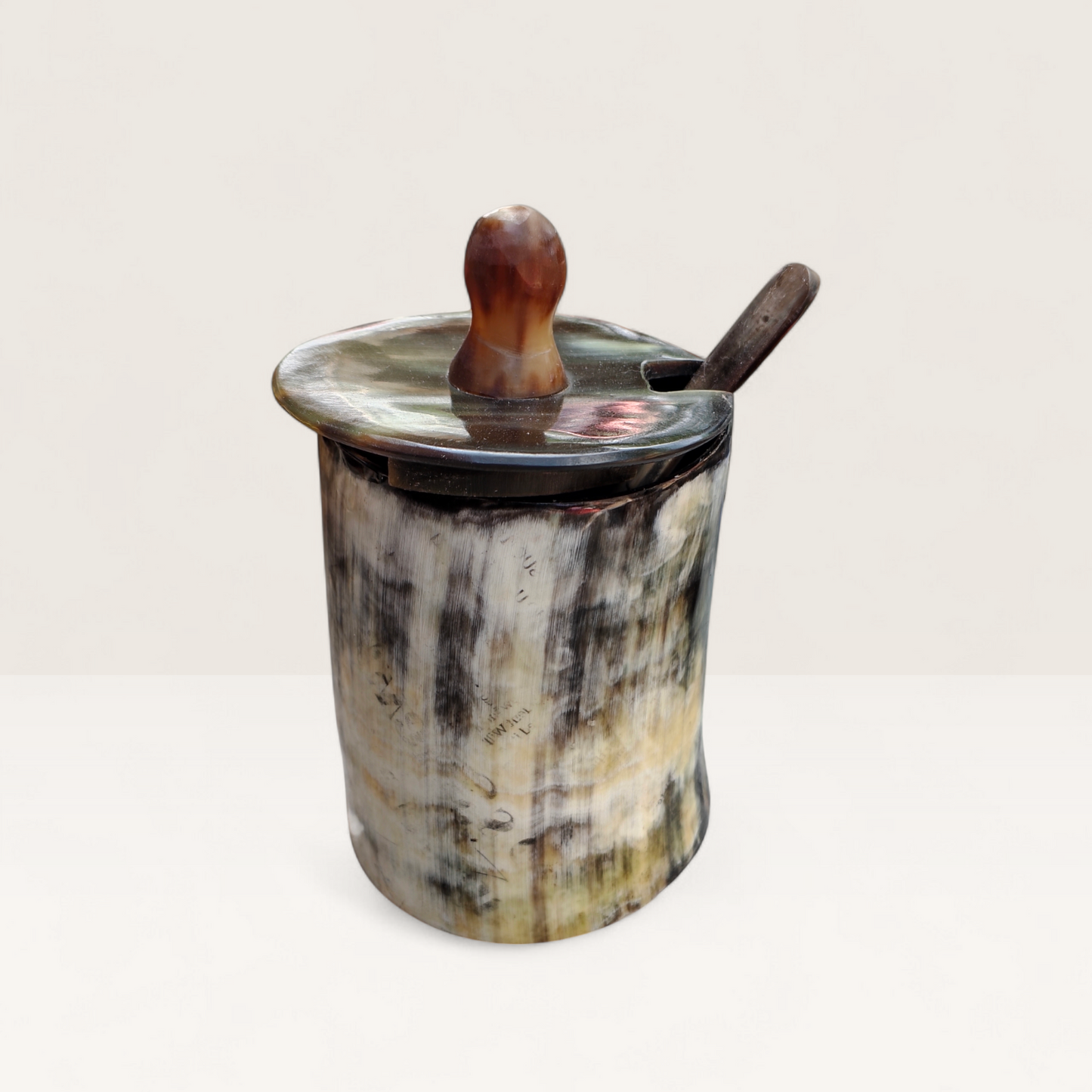 Handcrafted natural light marbled cream and charcoal Kenyan cow horn sugar bowl with a dark lid, spoon notch, and horn spoon, made in Kenya.