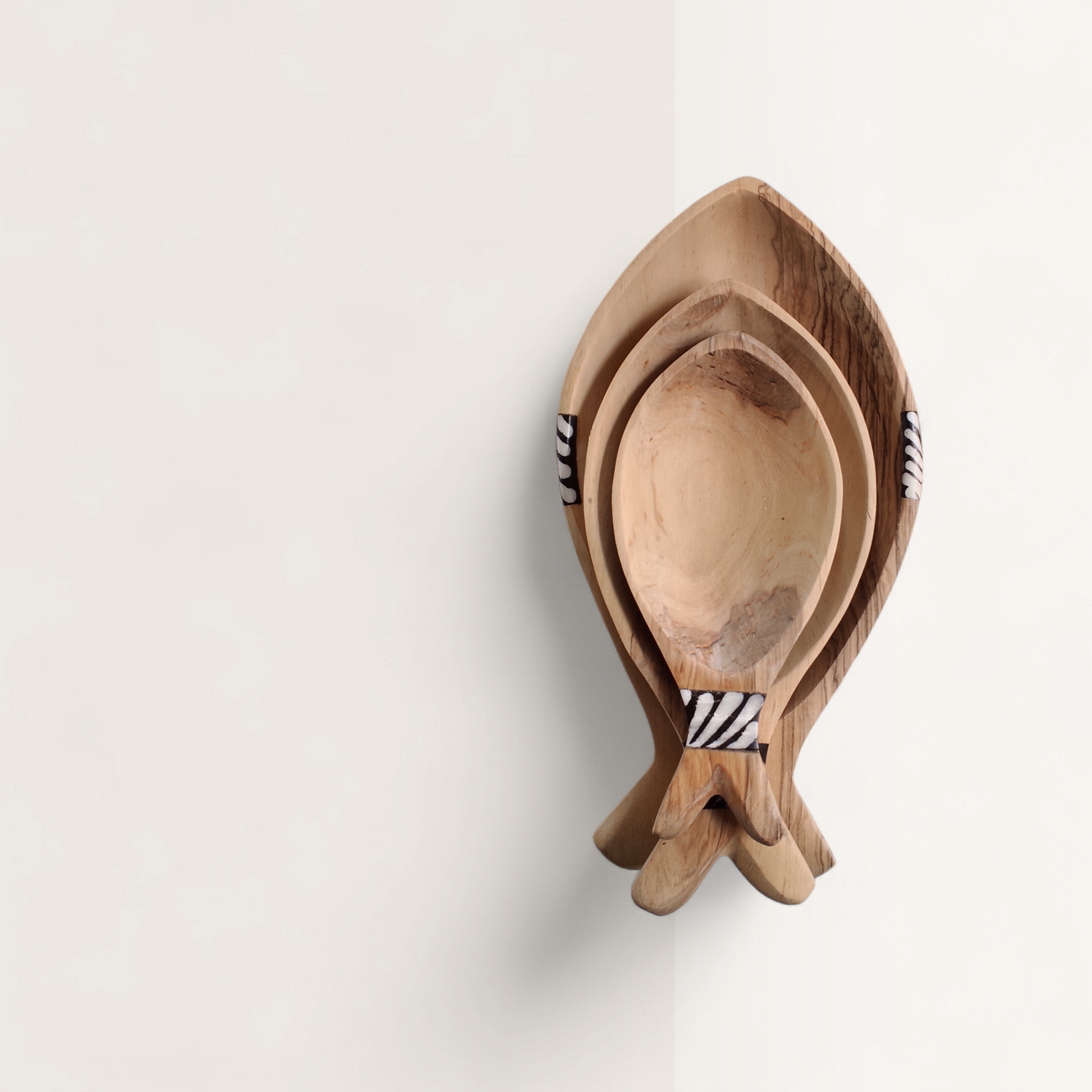 Top-down view of handcrafted 3-piece nesting Kenyan olive wood fish bowls with zebra stripe batik bone inlay accents, made in Ukambani Kenya.