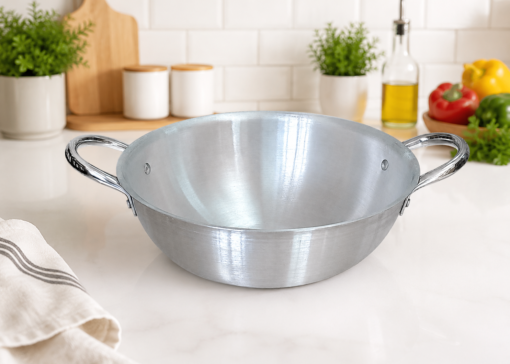 Kaluworks Premium heavy-gauge polished aluminium karai deep frying pan with double riveted loop handles displayed on a white kitchen counter next to a red product card