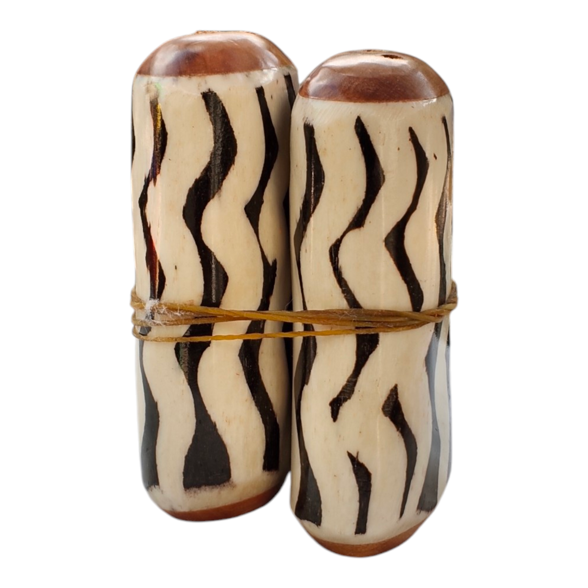 A pair of handcrafted Kenyan salt and pepper shakers made from polished bone with black and white batik zebra stripes and wood trim.