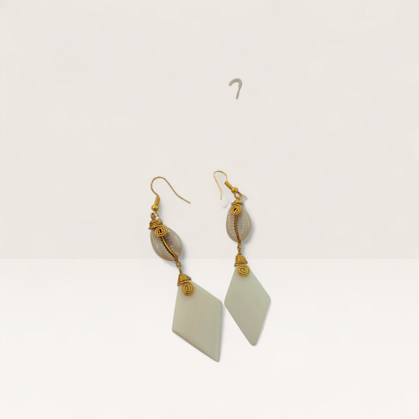 Handcrafted Kenyan drop earrings featuring white diamond-shaped bone, natural cowrie shells, and gold brass wire-wrap detailing