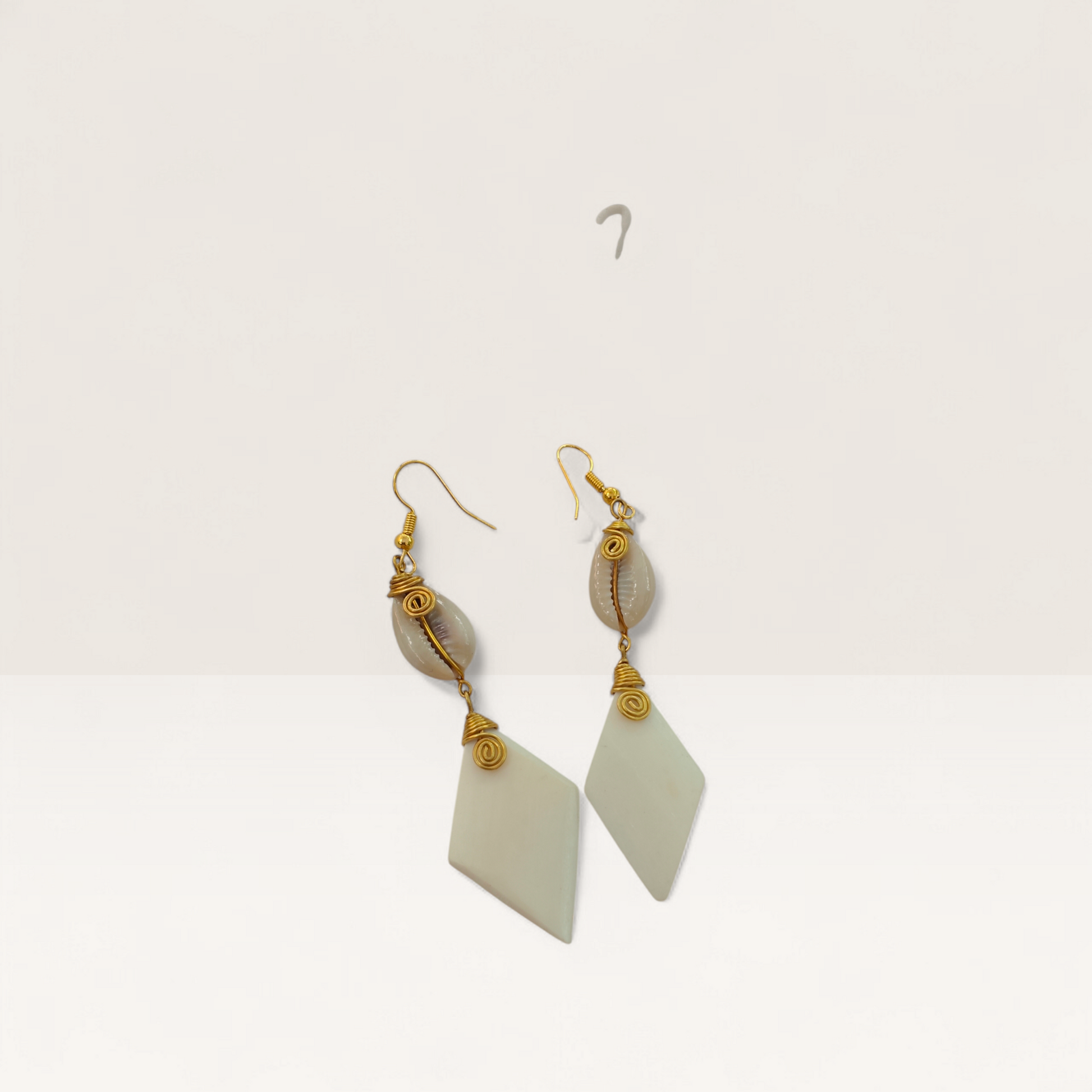 Handcrafted Kenyan drop earrings featuring white diamond-shaped bone, natural cowrie shells, and gold brass wire-wrap detailing