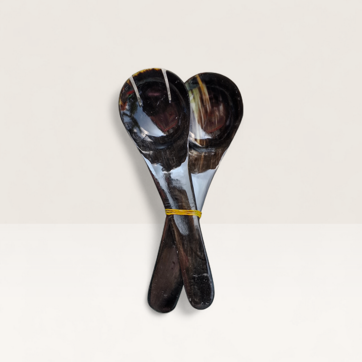Set of two hand-carved polished cow horn salad serving spoons with natural dark marbling, crafted in Kenya.