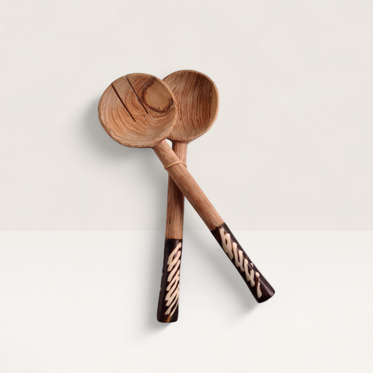 A pair of handcrafted Kenyan olive wood salad servers with black and white geometric batik-etched bone handles.