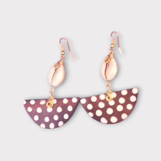 Handcrafted Kenyan earrings featuring a white cowrie shell and a semi-circular bone pendant with white polka dots on a dark background.