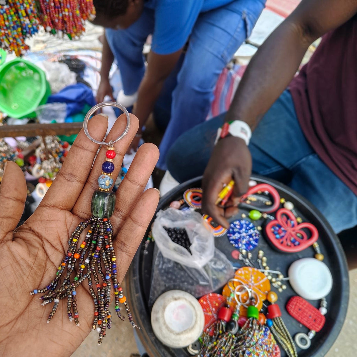 Nualocal handcrafted keychain with amber resin, iridescent glass beads, and a multi-strand tassel held in a hand.
