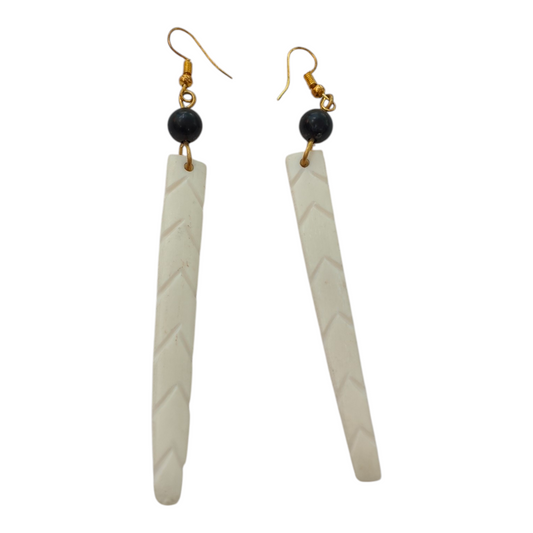 NuaLocal handcrafted off-white upcycled bone long bar drop earrings with carved chevron herringbone patterns and black bead accents, made in Kibera, Nairobi, Kenya.