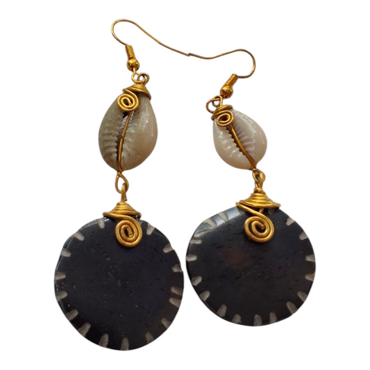 NuaLocal hand-carved dark brown upcycled bone circular disc drop earrings with white edge notches, wire-wrapped natural cowrie shells, and brass wire coils, made in Kibera, Nairobi, Kenya.