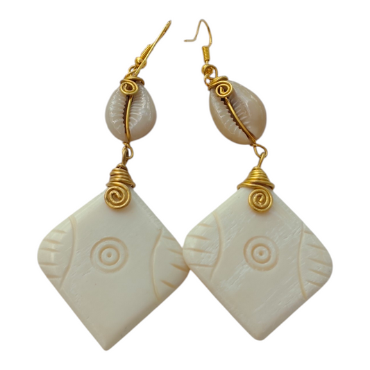 NuaLocal hand-carved off-white bone diamond-shaped drop earrings featuring etched concentric circle pattern, wire-wrapped natural cowrie shells, and brass wire coils, made in Kibera, Nairobi, Kenya