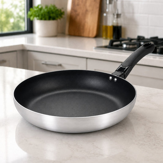 Nualocal Kaluworks Halisi non-stick aluminium frying pan with a brushed silver exterior and black Bakelite handle.