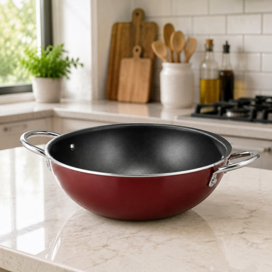 Nualocal Kaluworks non-stick aluminium deep karai with a crimson exterior and black interior on a kitchen countertop.