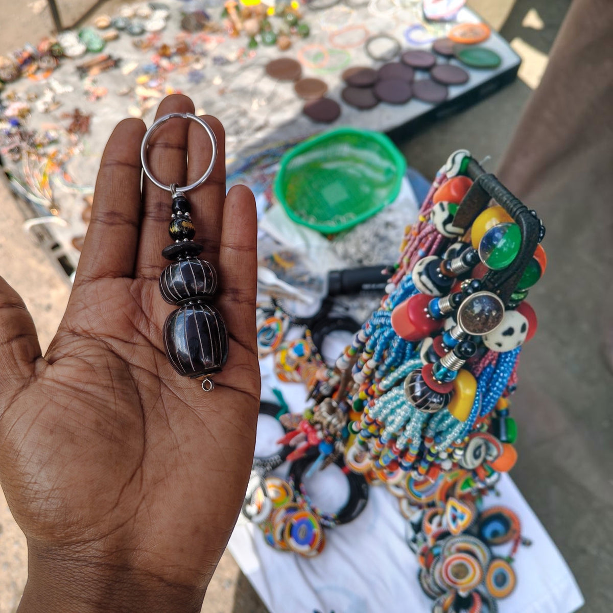 Nualocal handcrafted key holder with black batik-patterned upcycled bone and amber beads held in a person's palm.