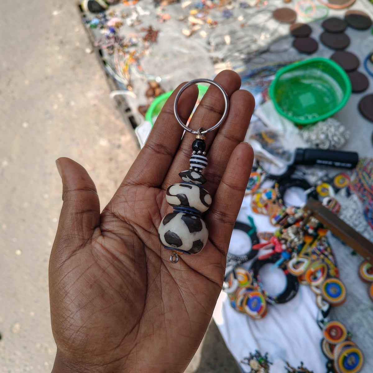 Nualocal handcrafted key holder featuring upcycled bone beads with batik patterns and amber resin in a palm of a hand