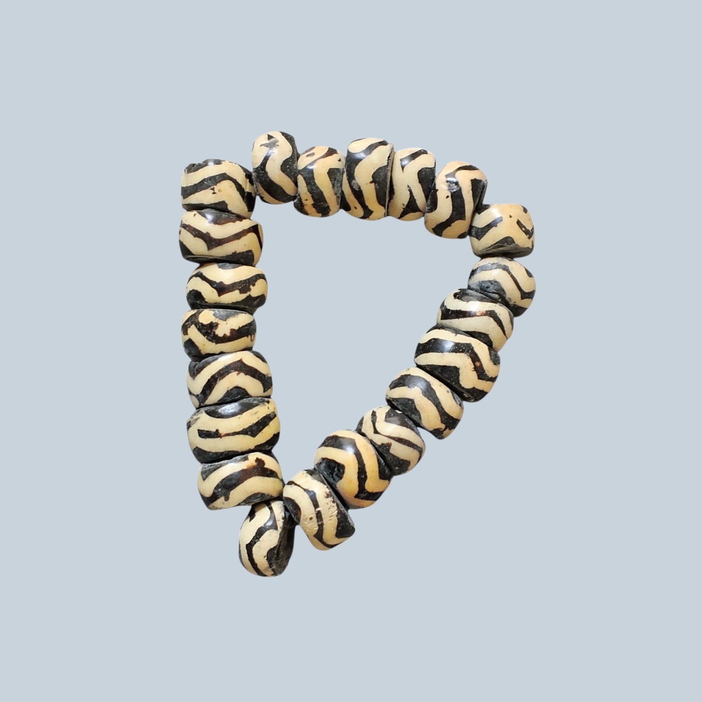 Nualocal hand-carved cylinder bone beads with black and ivory zebra stripe batik patterns in a triangular arrangement.