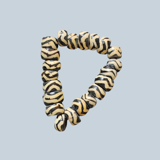 Nualocal hand-carved cylinder bone beads with black and ivory zebra stripe batik patterns in a triangular arrangement.