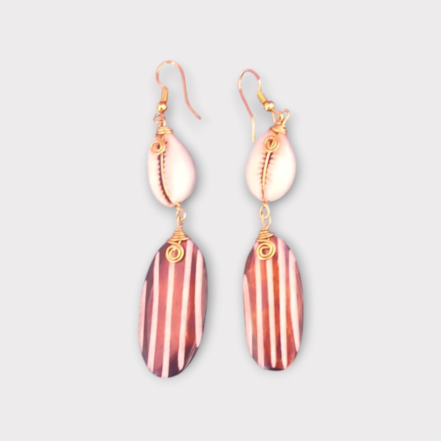 Handcrafted Kenyan earrings featuring a natural cowrie shell and a striped bone pendant.