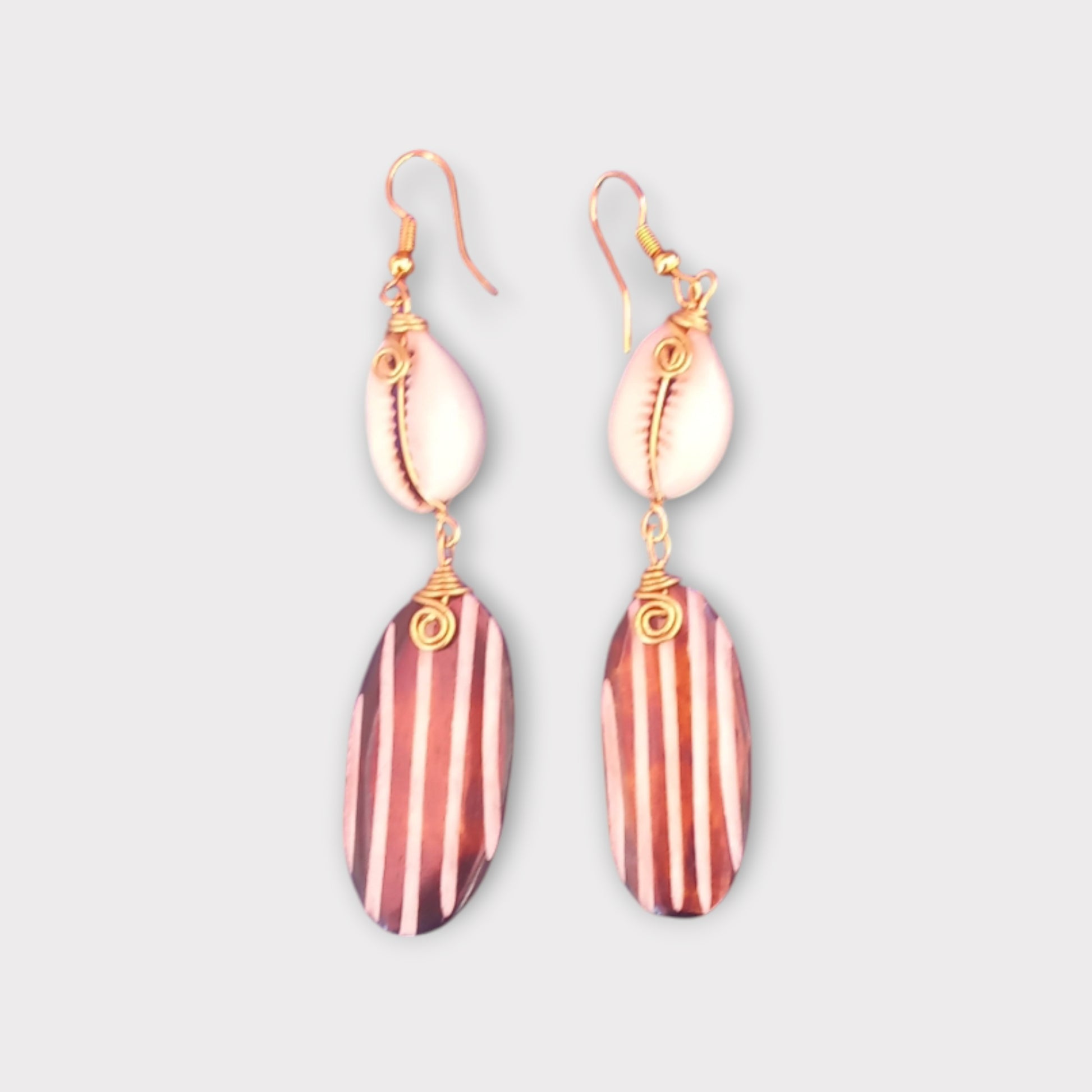 Handcrafted Kenyan earrings featuring a natural cowrie shell and a striped bone pendant.
