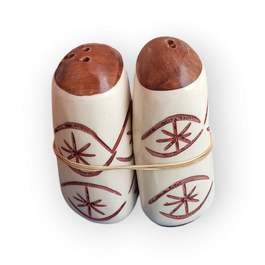 Unique handcrafted camel bone salt and pepper shakers from Kenya, featuring etched eye patterns and wooden tops, sold as a pair