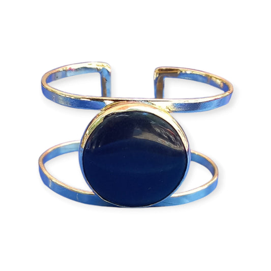 A handcrafted, adjustable brass bracelet from Kenya, designed as a double open cuff and featuring a striking, large black amber ornament.