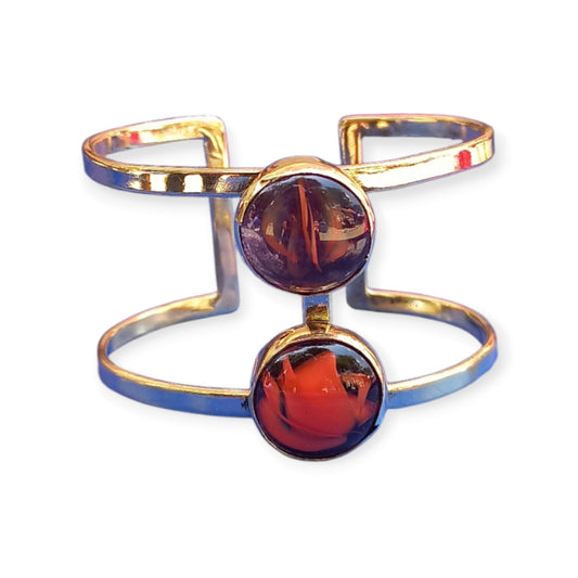 Adjustable open cuff bracelet made of polished brass from Kenya, showcasing two prominent, round honey-toned amber gemstones.