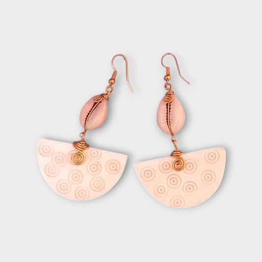 Dangle earrings with a small white cowrie shell connected to a larger, semi-circular bone piece with a carved concentric circle design, made in Kenya.