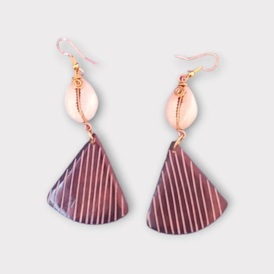A pair of unique dangle earrings made in Kenya, featuring a white cowrie shell and a modern triangular bone decorated with vertical stripes.