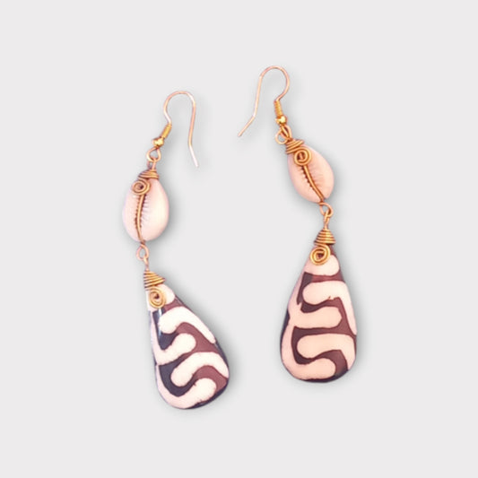 Handcrafted Kenyan earrings featuring a white cowrie shell and a teardrop-shaped bone pendant with a bold pattern.