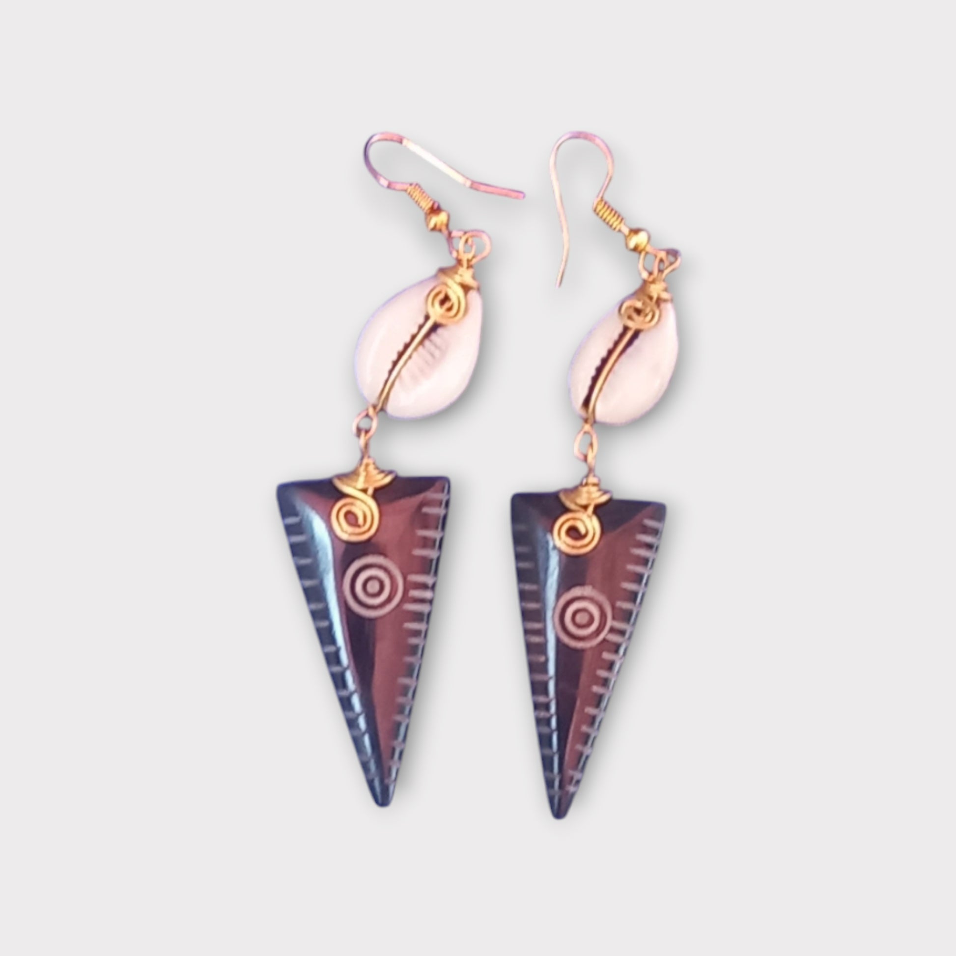 Modern tribal dangle earrings with a small white cowrie shell connected to a carved bone arrowhead, made in Kenya.