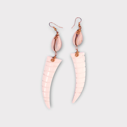 Handcrafted Kenyan earrings featuring a white cowrie shell and a curved, tusk-shaped bone pendant with carved ridges.